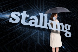 Businesswoman holding umbrella behind the word stalking