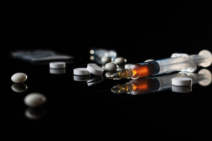 Different drugs - powder and pills and a syringe on a black background. Stop drug addiction. International Day against Drug abuse. Hard drugs on table.