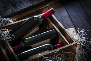 Red wine bottles packed in a wooden box shot rustic wooden table